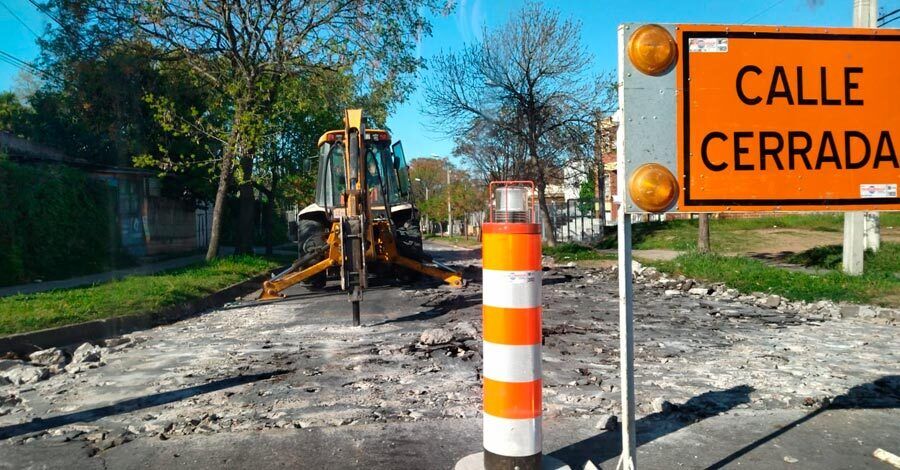 vista de la calle siendo taladrada por una retroexcavadora con martillo neumático y un cartel de calle cerrada