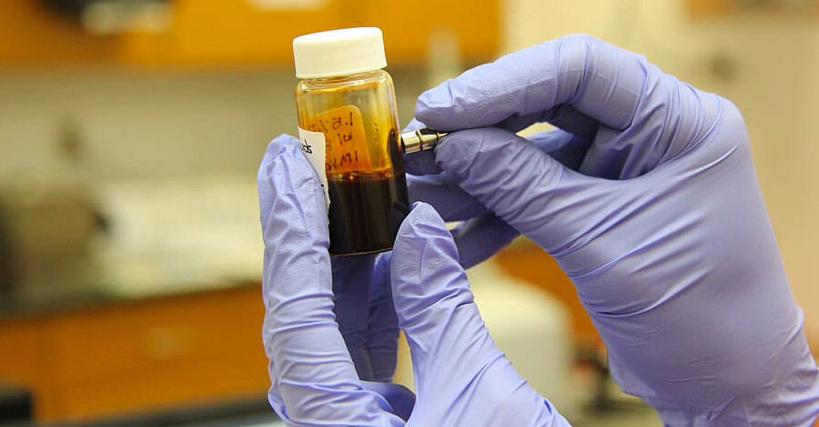 manos con guantes de látex etiquetando un frasco con una muestra de sangre