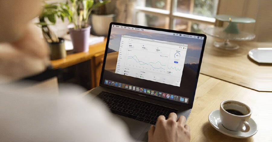 una persona vista desde atrás sentada en un escritorio trabajando con un laptop
