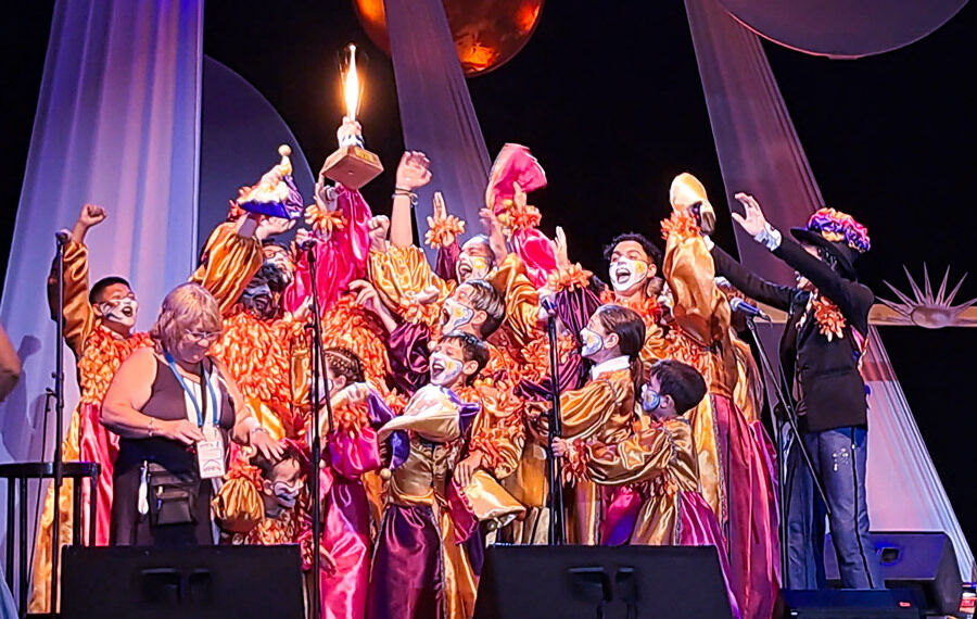 Murga La Zafada, foto del momento en que la murga, vestida con sus trajes de gala, tela de raso colores naranja, fucsia y violeta, reciben el trofeo