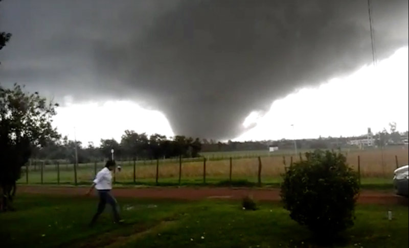 Se ve un campo, al horizonte parcialmente se ve el cielo y un gigantesco tornado